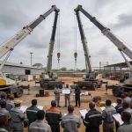 Create an editorial news illustration for an article about 'AGL Congo renforce la sécurité : 25 employés certifiés à la conduite de grues mobiles'. The specific country is Republique du Congo (Brazzaville) (CG); make visual cues accurate to this exac