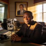 Create an editorial news illustration for an article about 'André Yabi Yabi, légende de Radio Congo, s’éteint : la nation rend hommage à sa voix inoubliable'. The specific country is Republique du Congo (Brazzaville) (CG); make visual cues accurate t