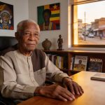 Create an editorial news illustration for an article about 'Bernard Mackiza, figure emblématique du journalisme congolais, se livre dans «Cartes sur table» à 92 ans'. The specific country is Republique du Congo (Brazzaville) (CG); make visual cues ac