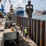 Create an editorial news illustration for an article about 'Modernisation du port de Pointe-Noire : le battage des pieux du Môle Est s’achève avec succès'. The specific country is Republique du Congo (Brazzaville) (CG); make visual cues accurate to t