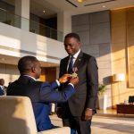 Create an editorial news illustration for an article about 'Norbert Okiokoutina fait Grand commandeur de l’ordre du mérite de la Cémac'. The specific country is Republique du Congo (Brazzaville) (CG); make visual cues accurate to this exact country a
